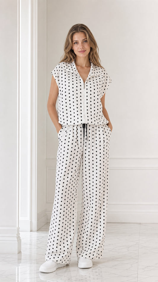 Full front view of model wearing white and black polka dot two-piece matching set with wide leg pants