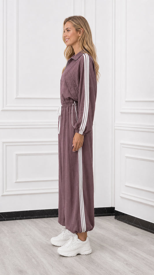Side profile of woman wearing a mauve sporty jumpsuit with side stripe detail