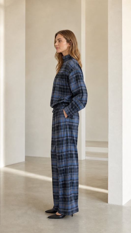 Side profile view of model in relaxed blue plaid blouse and wide leg matching pants
